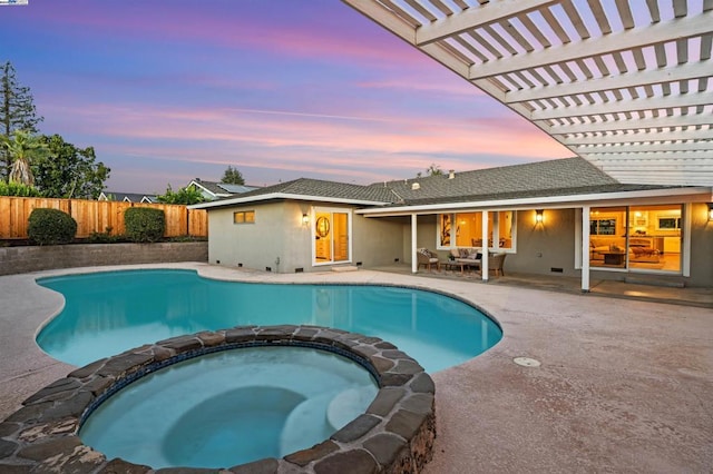 pool at dusk featuring an in ground hot tub and a patio