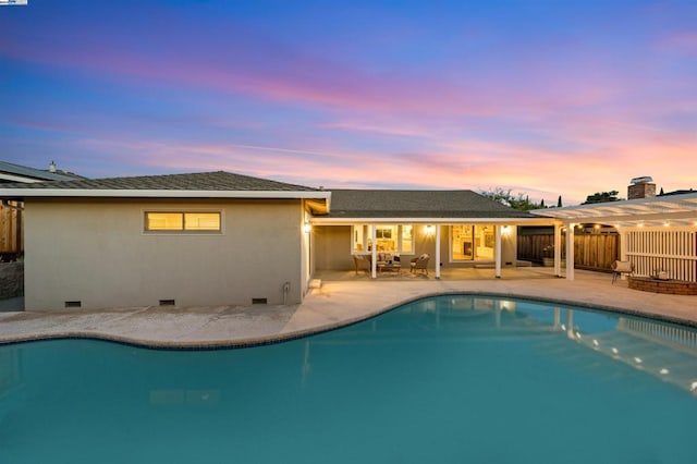 pool at dusk featuring a patio