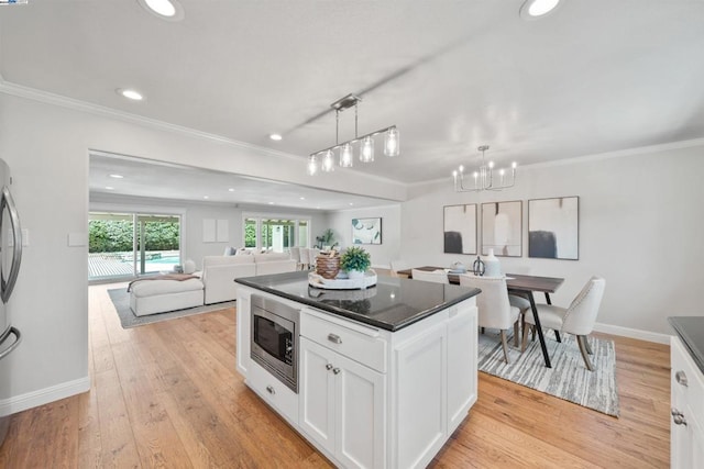 kitchen with white cabinets, a kitchen island, decorative light fixtures, stainless steel appliances, and light hardwood / wood-style floors