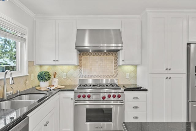 kitchen with tasteful backsplash, sink, white cabinetry, appliances with stainless steel finishes, and wall chimney exhaust hood