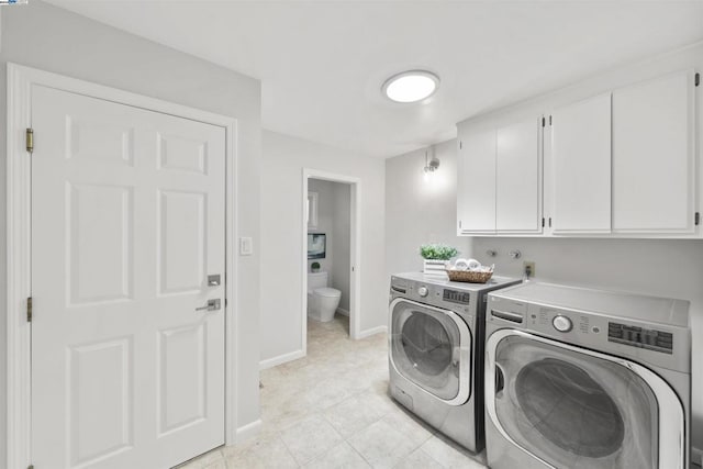 laundry room with light tile patterned flooring, cabinets, and washing machine and clothes dryer