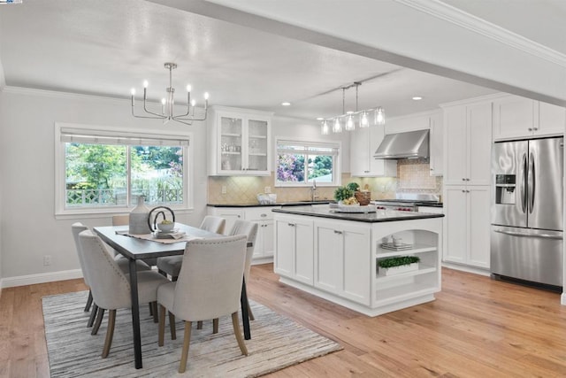 dining area featuring crown molding, light wood-type flooring, sink, and an inviting chandelier