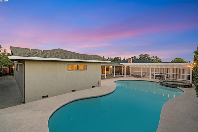 pool at dusk featuring a patio area and an in ground hot tub