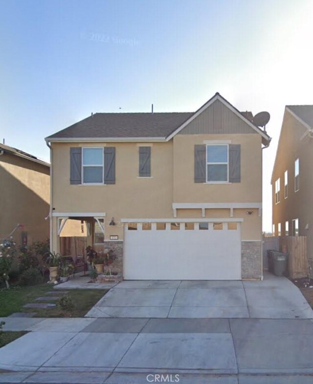 view of front of home featuring fence, stucco siding, a garage, stone siding, and driveway