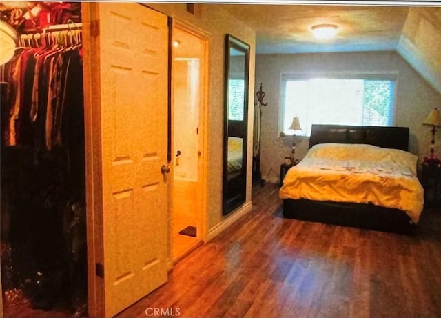 bedroom with vaulted ceiling, a closet, and wood-type flooring