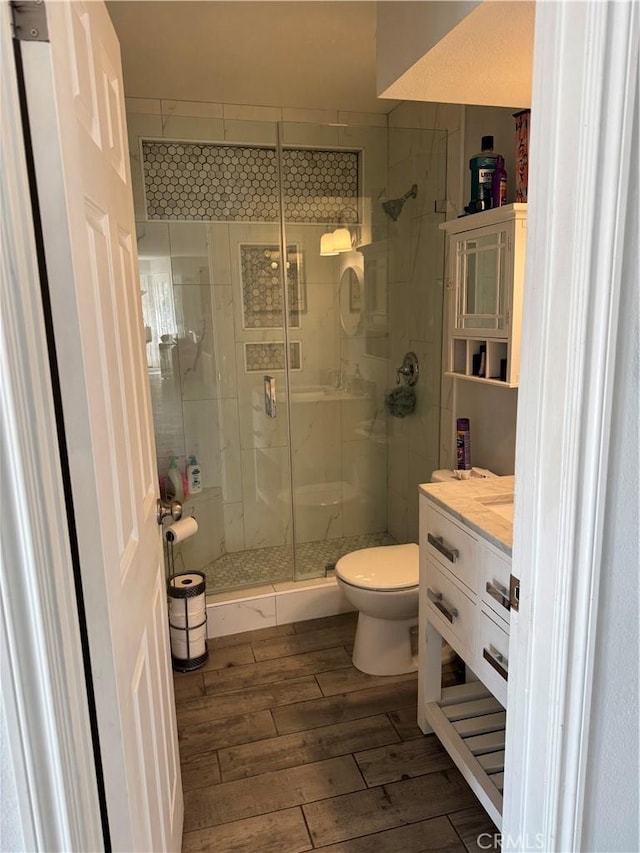 bathroom with toilet, an enclosed shower, and vanity