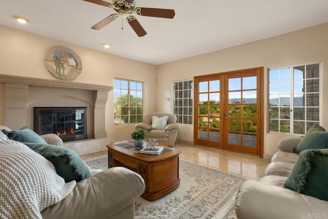 tiled living room featuring ceiling fan, a tiled fireplace, a mountain view, and french doors