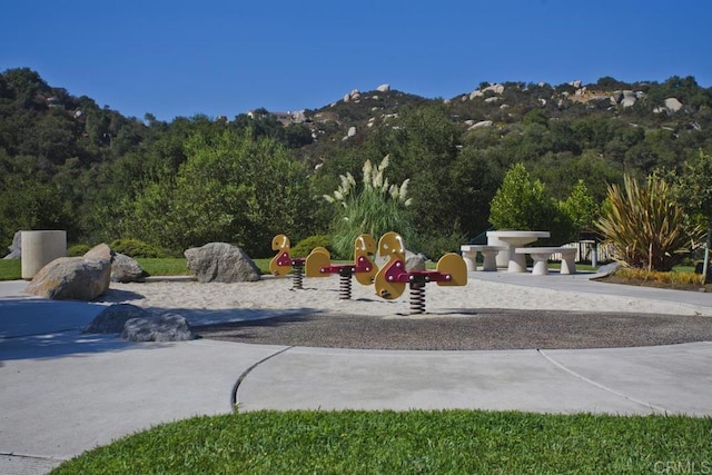 surrounding community featuring a playground and a mountain view