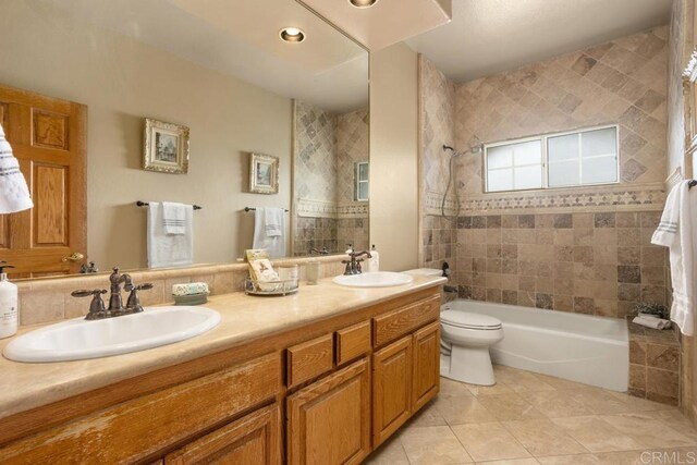 full bathroom featuring toilet, tile patterned flooring, tiled shower / bath combo, and vanity