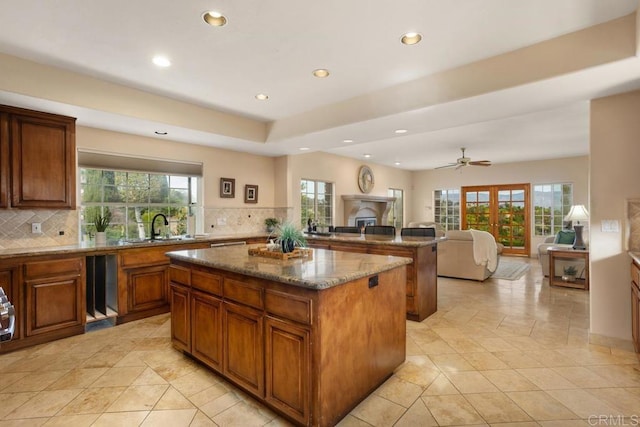 kitchen featuring ceiling fan, dark stone countertops, a center island, sink, and french doors