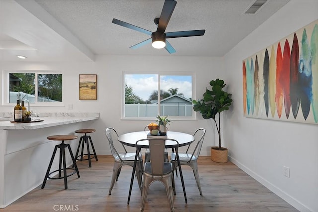 dining space with a textured ceiling, light hardwood / wood-style flooring, and ceiling fan