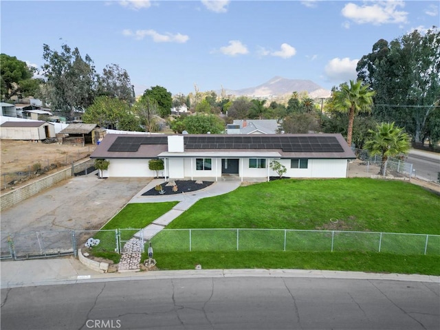 single story home featuring a mountain view, solar panels, and a front yard