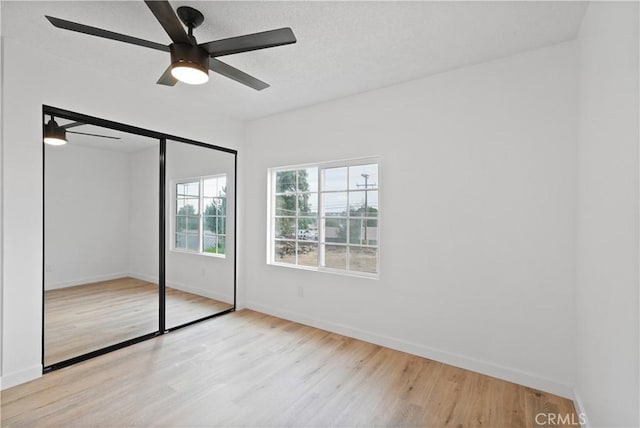 unfurnished bedroom featuring ceiling fan, a closet, and light hardwood / wood-style flooring