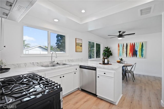 kitchen with white cabinets, sink, stainless steel dishwasher, light hardwood / wood-style floors, and kitchen peninsula