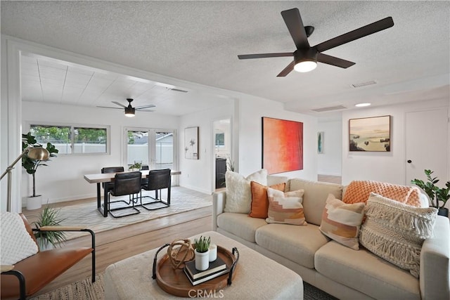 living room featuring a textured ceiling, light hardwood / wood-style flooring, and ceiling fan