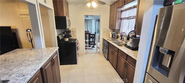 kitchen featuring appliances with stainless steel finishes, sink, light tile patterned flooring, ceiling fan, and light stone counters