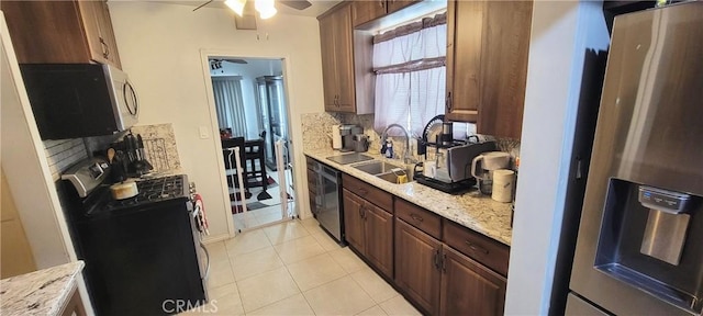 kitchen featuring washer / clothes dryer, stainless steel appliances, sink, light tile patterned flooring, and light stone counters