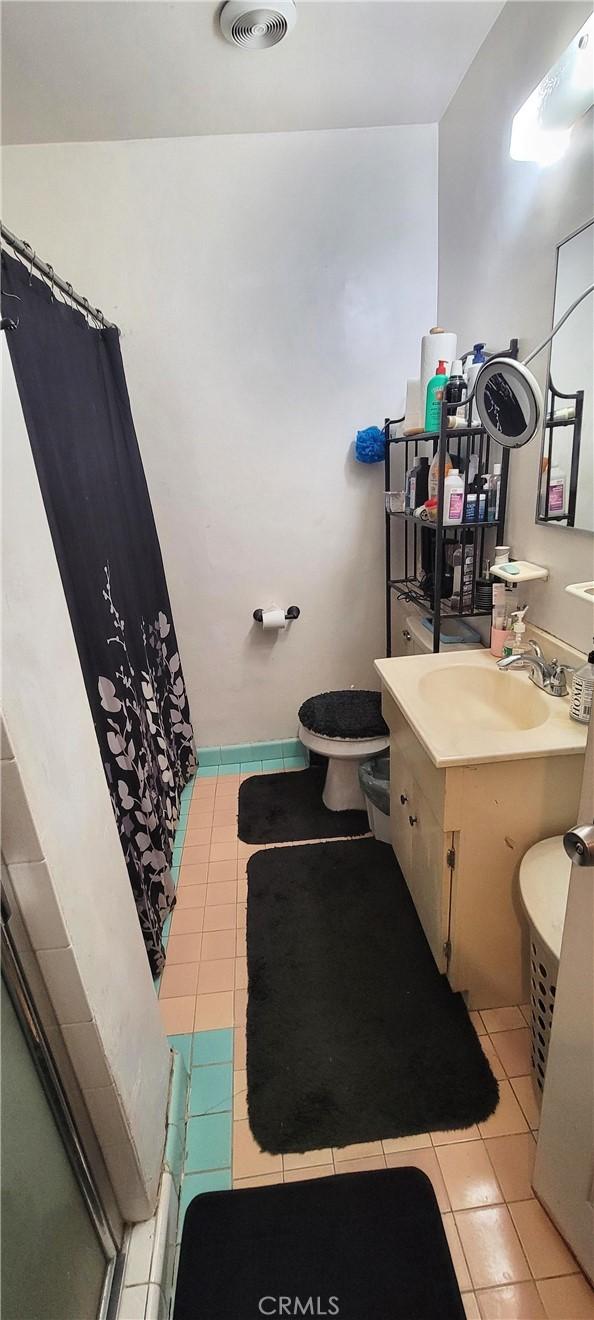 bathroom with toilet, vanity, a shower with shower curtain, and tile patterned flooring