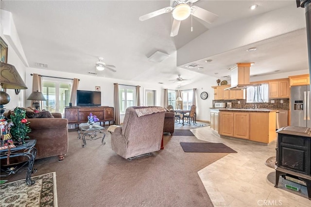 living room with light colored carpet, lofted ceiling, and a wood stove