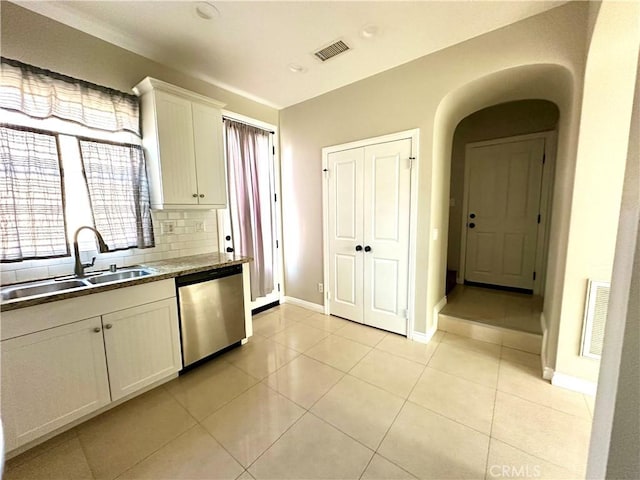 kitchen with white cabinets, sink, stainless steel dishwasher, light tile patterned flooring, and tasteful backsplash