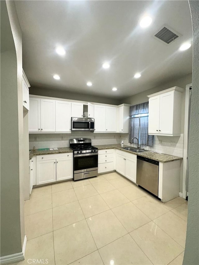 kitchen featuring sink, stainless steel appliances, white cabinetry, and light tile patterned floors