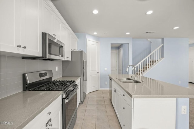 kitchen featuring appliances with stainless steel finishes, sink, an island with sink, white cabinetry, and light tile patterned flooring