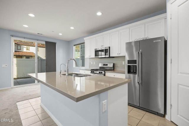 kitchen featuring light carpet, white cabinets, sink, an island with sink, and stainless steel appliances