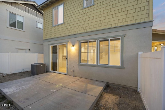 back house at dusk with central AC and a patio area