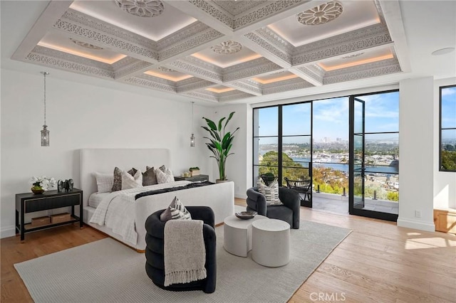 bedroom featuring light hardwood / wood-style floors, a water view, beam ceiling, and coffered ceiling