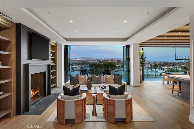 living room featuring light hardwood / wood-style floors, plenty of natural light, and a tray ceiling