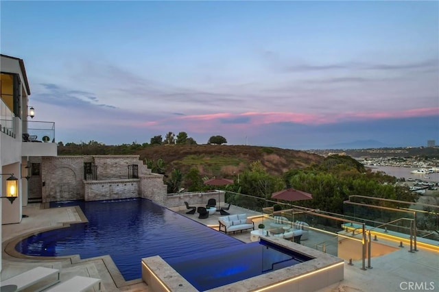 pool at dusk featuring outdoor lounge area