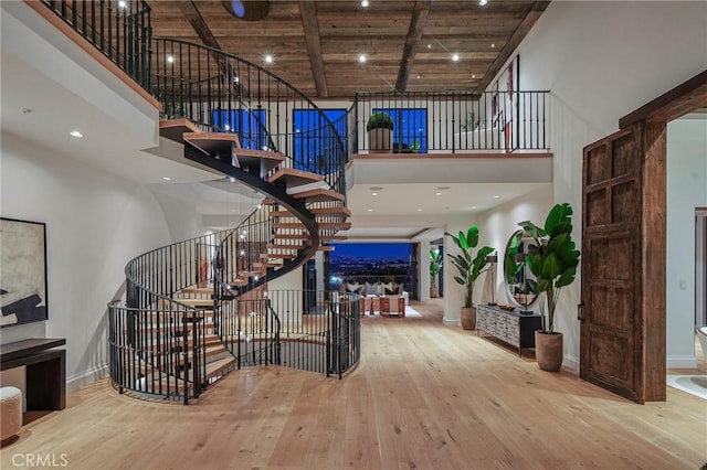 stairway featuring wood ceiling, wood-type flooring, beamed ceiling, and a high ceiling