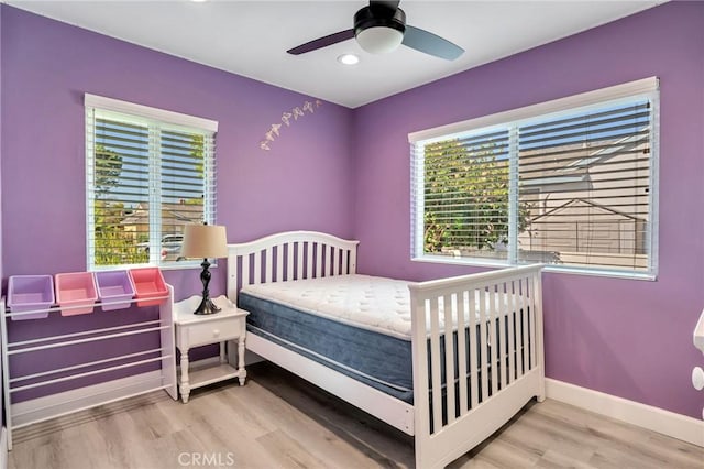 bedroom featuring ceiling fan, light wood-type flooring, and multiple windows