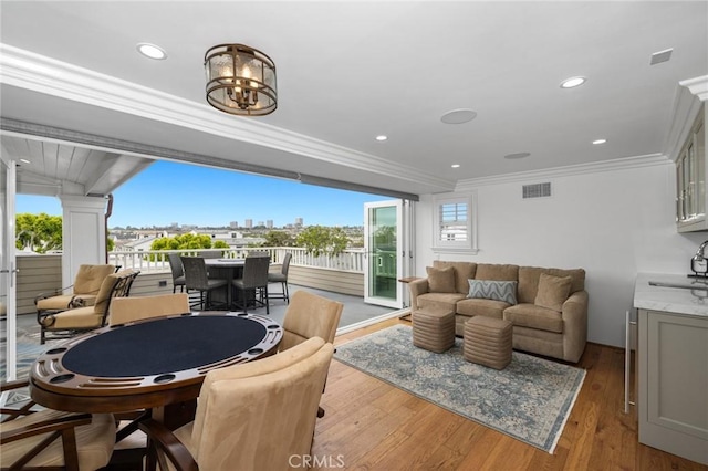 living room with sink, light hardwood / wood-style floors, a notable chandelier, and ornamental molding