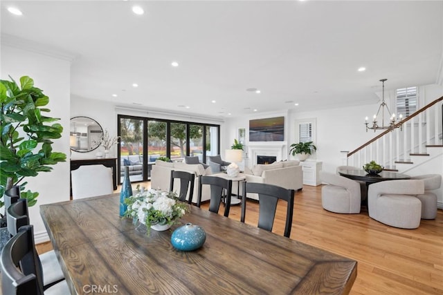 dining space featuring light hardwood / wood-style flooring, an inviting chandelier, and ornamental molding