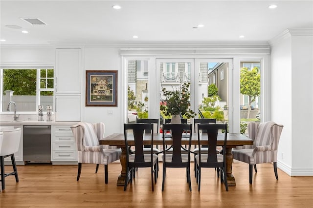 dining space featuring plenty of natural light, light hardwood / wood-style floors, sink, and crown molding