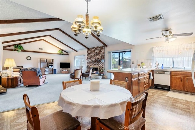 dining room with lofted ceiling with beams, ceiling fan with notable chandelier, and a brick fireplace