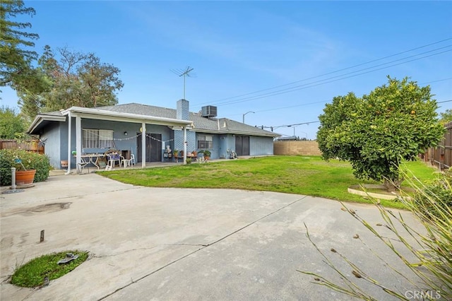 back of house with central air condition unit, a patio area, and a yard