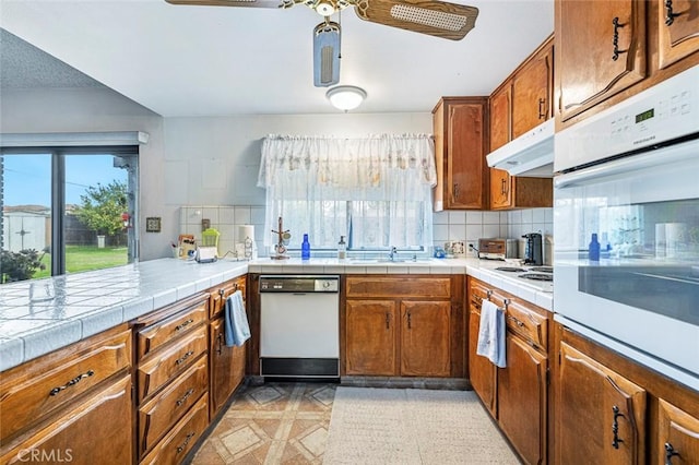 kitchen featuring tasteful backsplash, tile countertops, ceiling fan, and white appliances