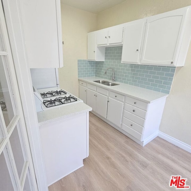 kitchen featuring white gas stovetop, sink, light hardwood / wood-style flooring, decorative backsplash, and white cabinetry