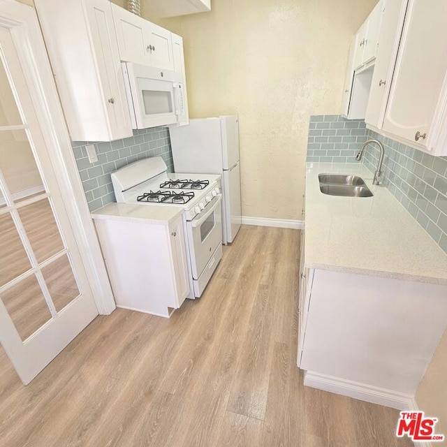 kitchen with decorative backsplash, light wood-type flooring, white appliances, sink, and white cabinetry