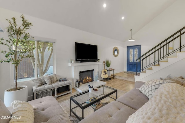 living room with light wood-type flooring, vaulted ceiling, and a fireplace