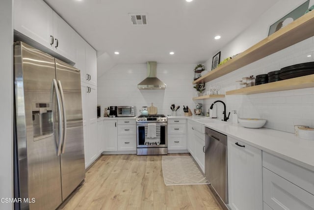 kitchen with white cabinetry, wall chimney range hood, stainless steel appliances, and tasteful backsplash