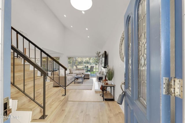 entryway with light hardwood / wood-style flooring and a towering ceiling