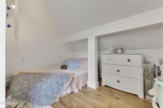 bedroom featuring light wood-type flooring and lofted ceiling