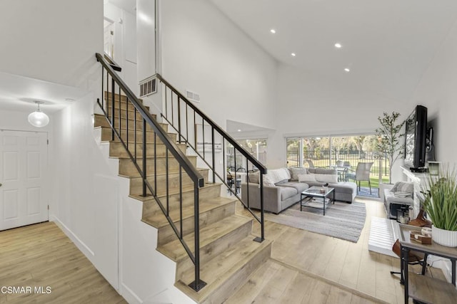 stairs with hardwood / wood-style flooring and a high ceiling