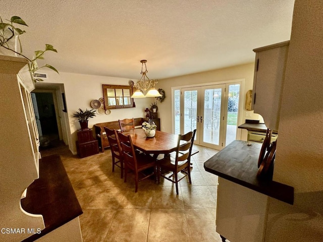 dining space featuring french doors, a textured ceiling, and an inviting chandelier