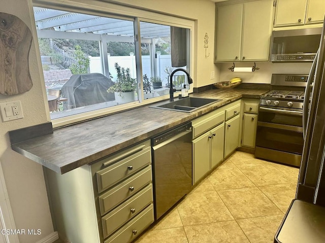 kitchen featuring butcher block counters, sink, light tile patterned flooring, and appliances with stainless steel finishes