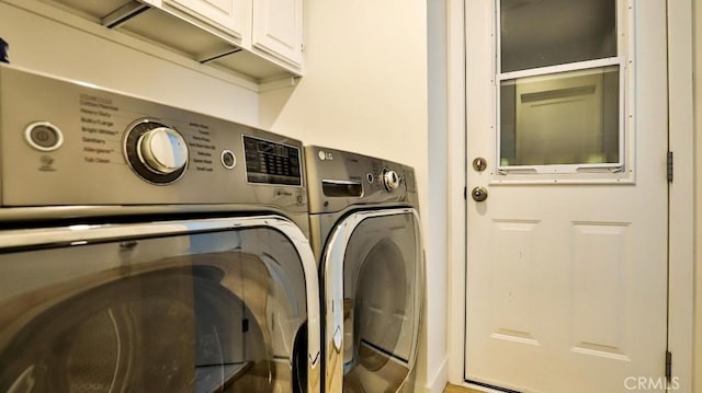 clothes washing area with cabinets and washer and clothes dryer