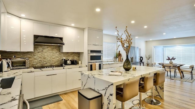 kitchen featuring a center island, light hardwood / wood-style flooring, double oven, stovetop, and white cabinets